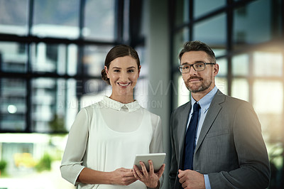 Buy stock photo Portrait of two businesspeople looking over a tablet in the office