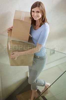 Buy stock photo Portrait of a happy young woman carrying boxes while moving out of her house