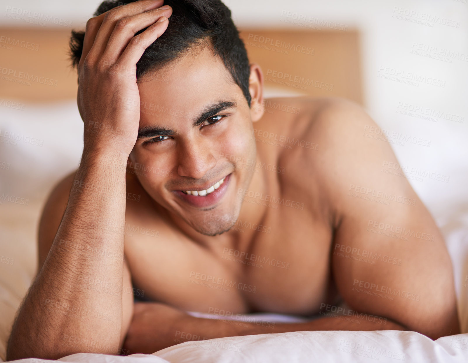 Buy stock photo Portrait of a happy young man lying in bed feeling well rested