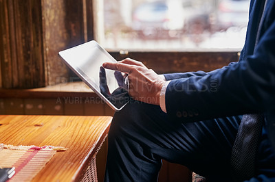 Buy stock photo Cropped shot of a well-dressed mature man using a digital tablet in a cafe after work
