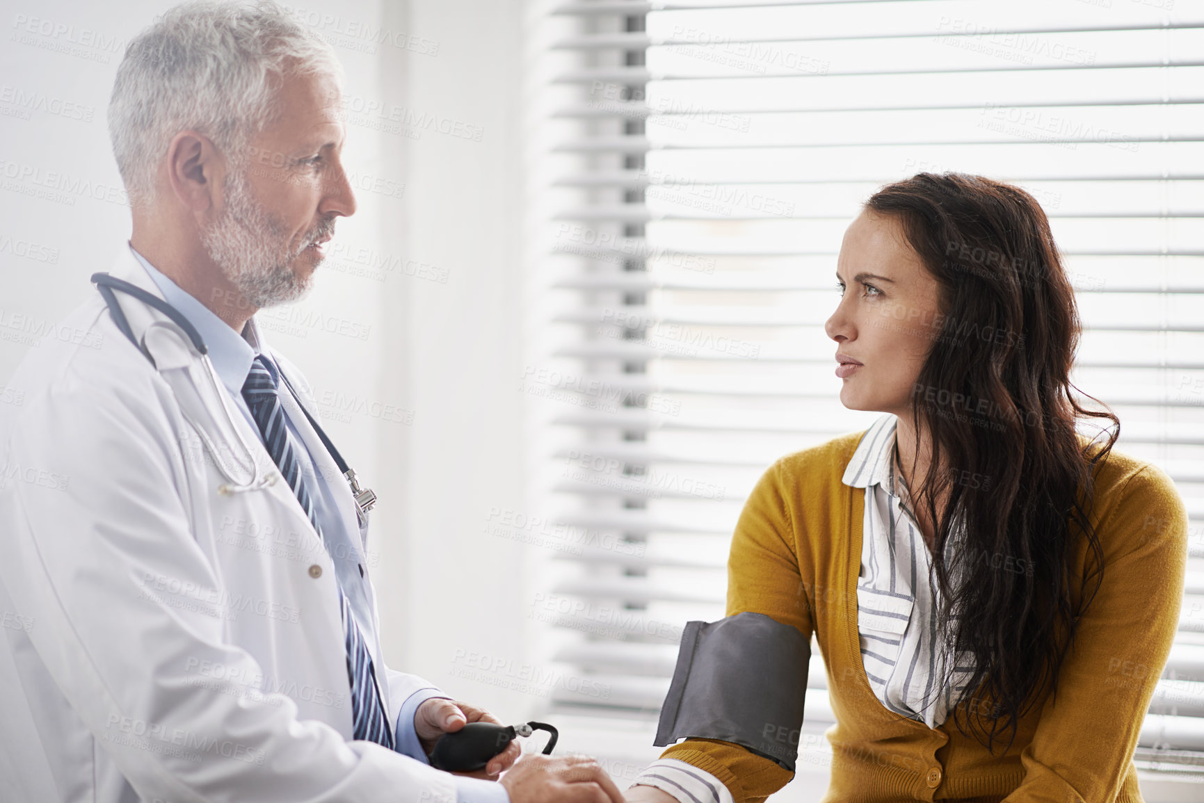 Buy stock photo Doctor, blood pressure and woman talking at hospital with medical consultation for health insurance. Healthcare, stethoscope and check pulse for medical exam, wellness and hypertension diagnosis