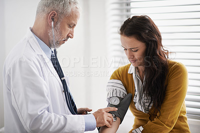 Buy stock photo Shot of a doctor checking a patient's blood pressure