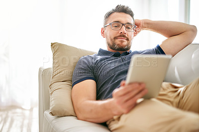 Buy stock photo Tablet, relax and man on a sofa in the living room watching a video on social media or the internet. Rest, browsing and mature male person reading an online blog on digital technology at his home.