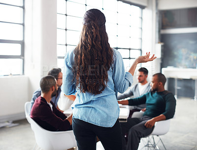 Buy stock photo Rearview shot of a woman giving a presentation to colleagues in an office