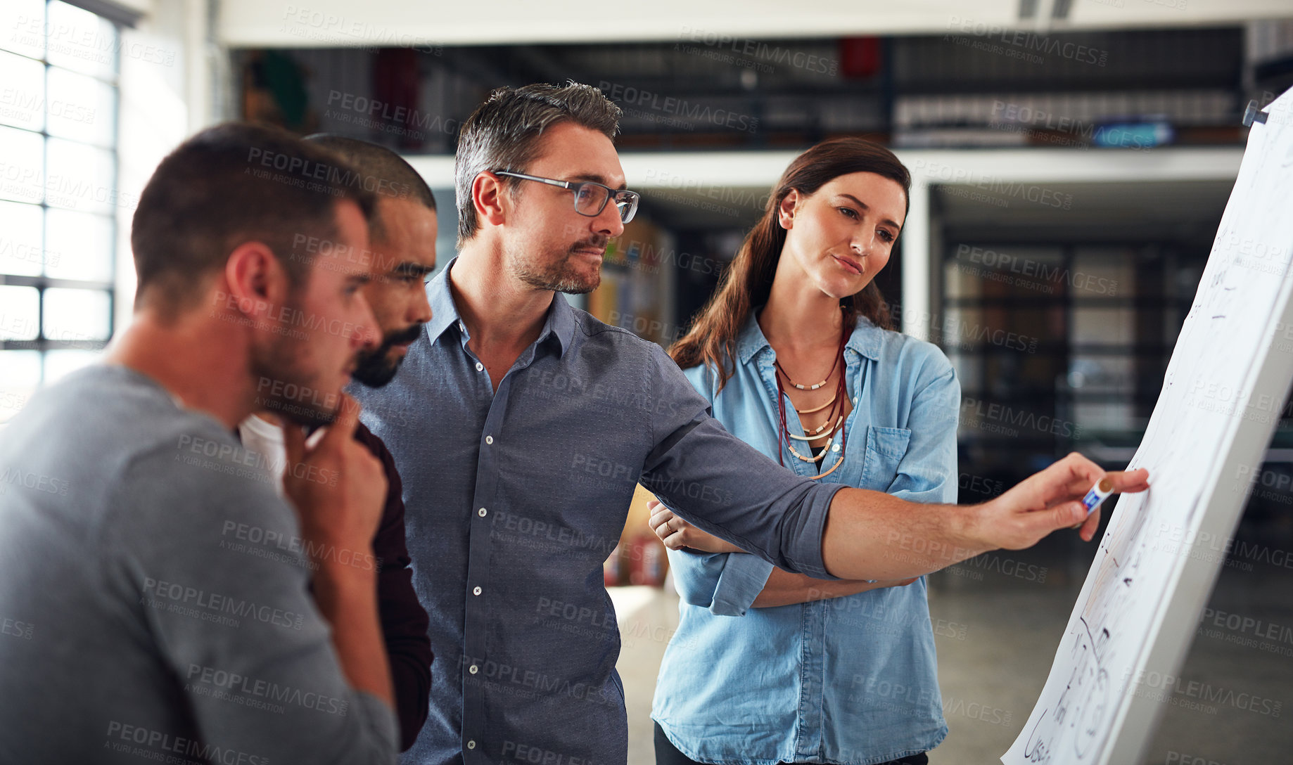 Buy stock photo Shot of a group of colleagues brainstorming together on a whiteboard in an office