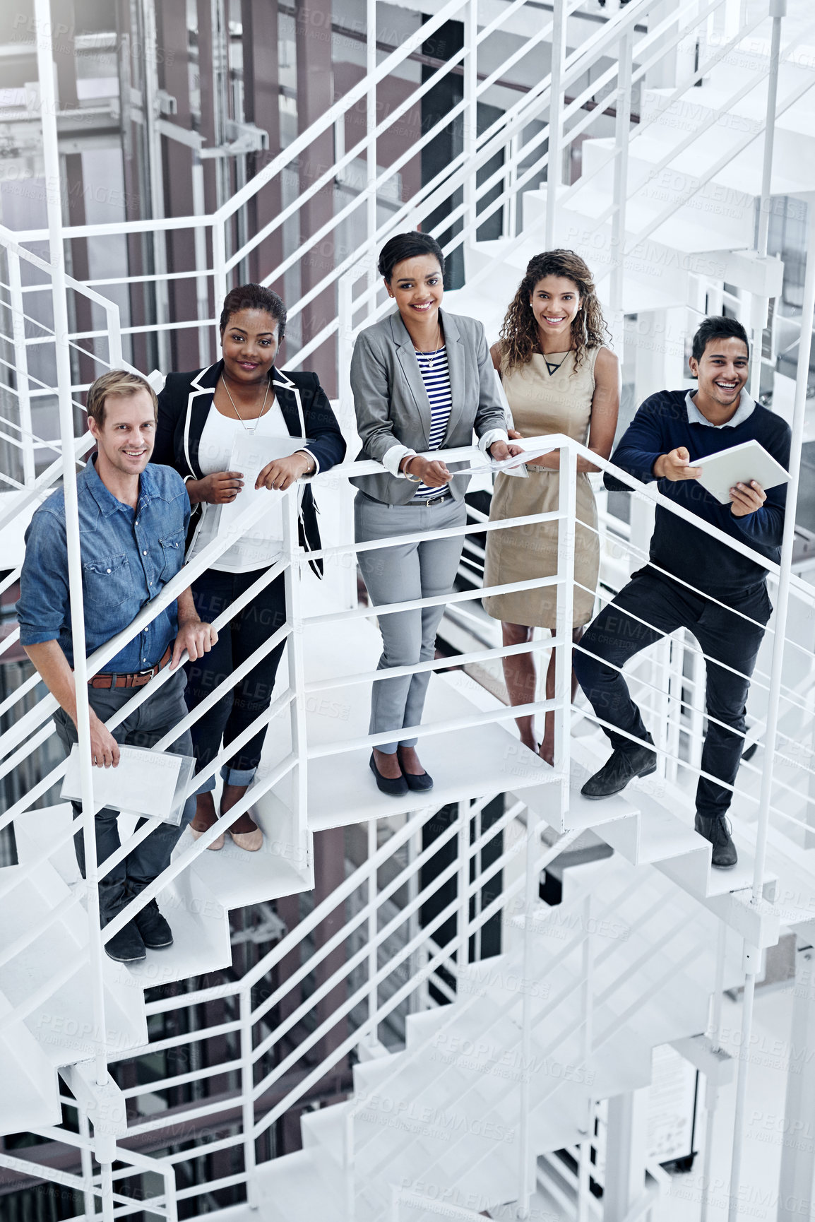 Buy stock photo Portrait of a group of smiling coworkers standing on stairs in a modern office