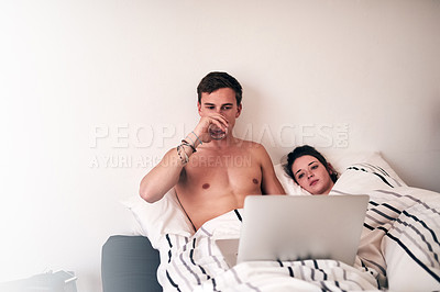 Buy stock photo Shot of a young couple using their laptop in bed