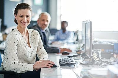 Buy stock photo Portrait of a young woman working at her computer in an office with colleagues in the background