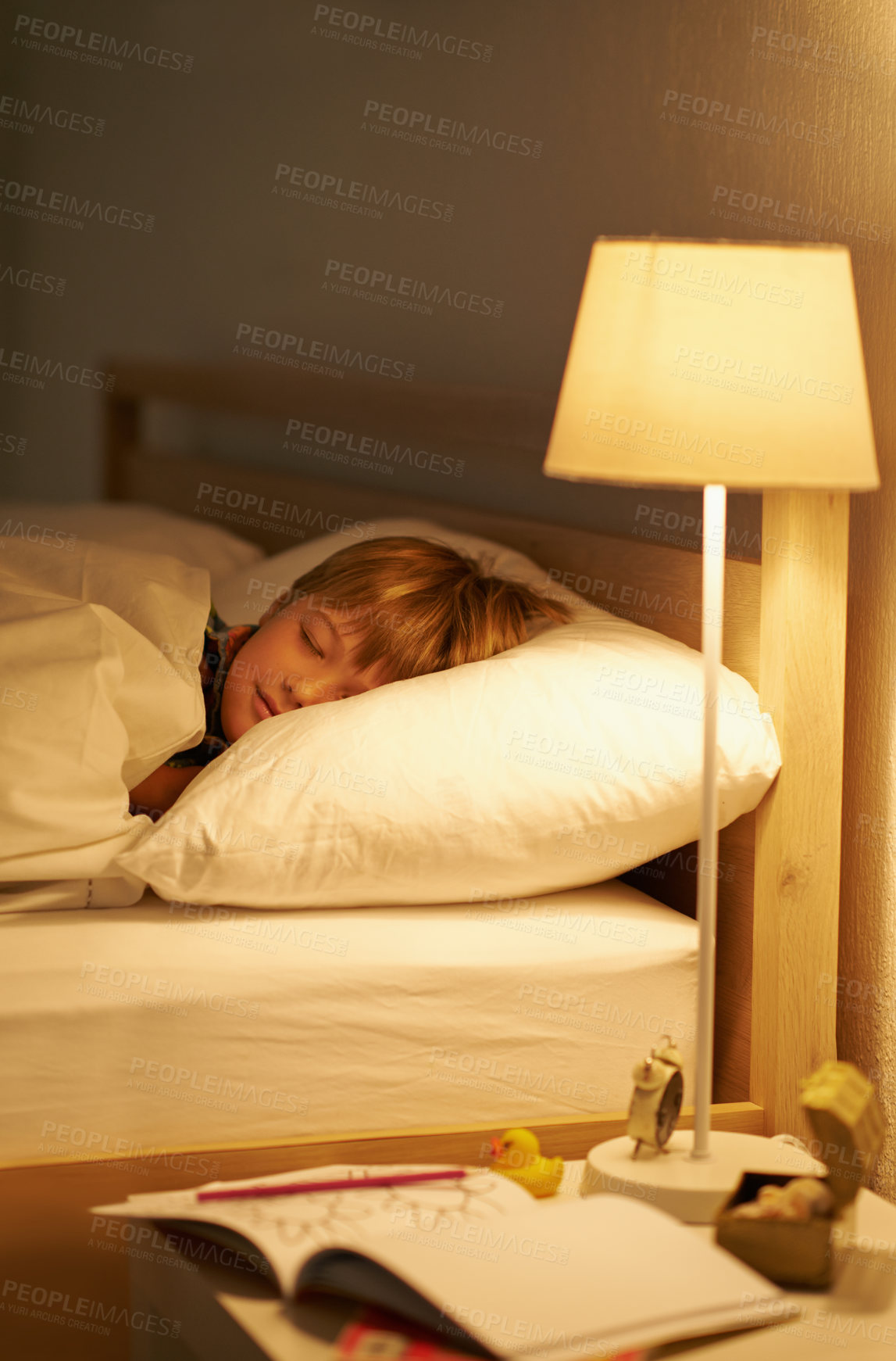 Buy stock photo Boy, bedroom and rest for night, sleeping and tired with fatigue and peace. Child, dreaming and exhausted with pyjamas, carefree and bed with lamp for serene childhood at home or house for calm kid