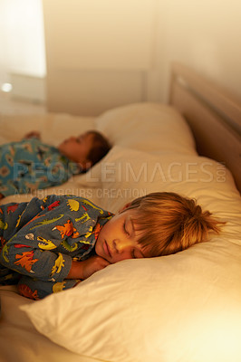Buy stock photo Children, bed and rest for night, sleeping and tired with fatigue and peace. Brothers, dreaming and exhausted with pyjamas, onesie and bedroom with lamp for serene childhood at home or house for kids
