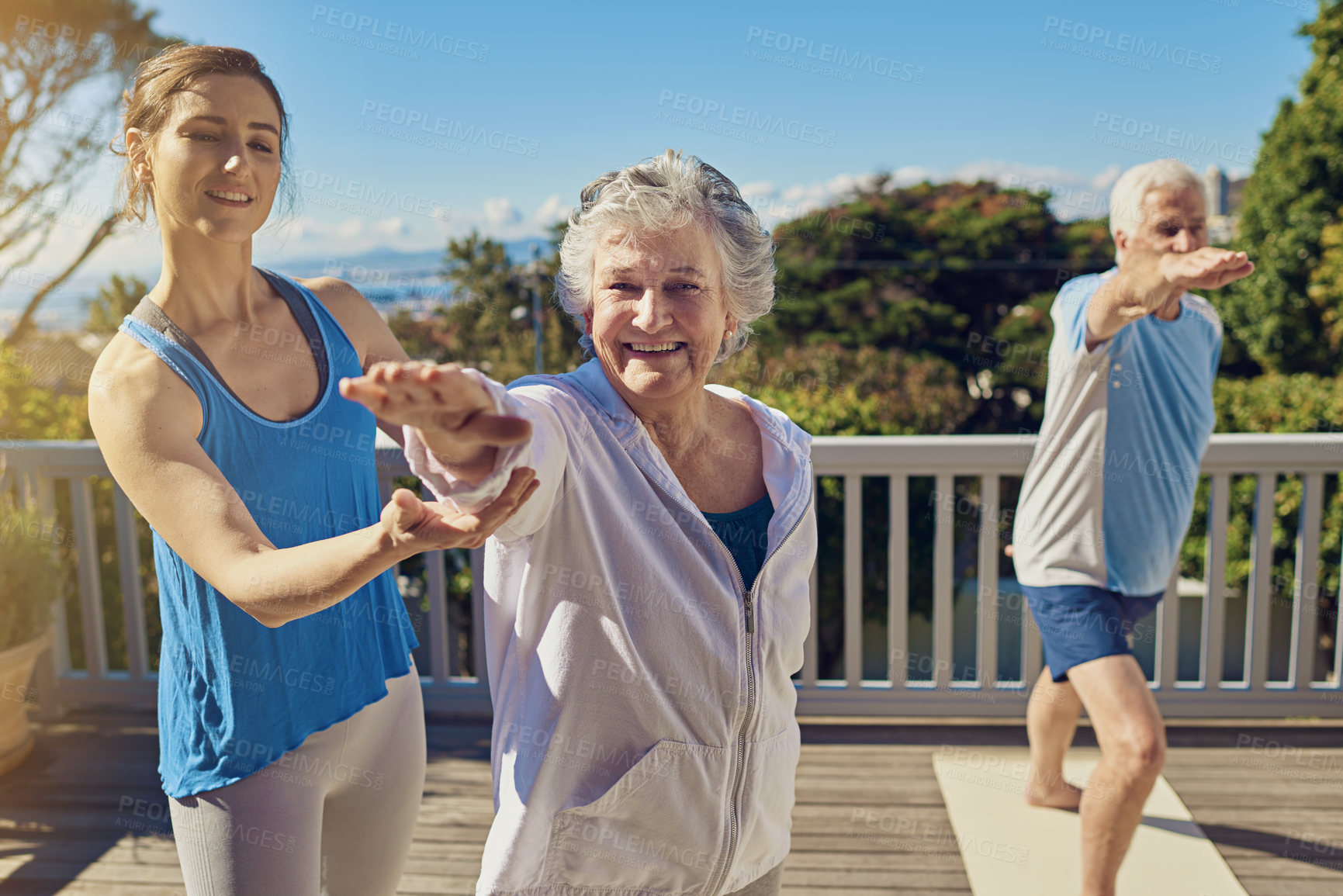 Buy stock photo Shot of a senior couple doing yoga together with an instructor on their patio outside