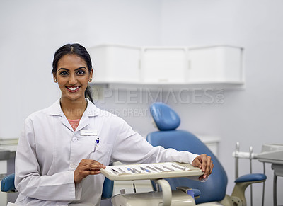 Buy stock photo Portrait of a young female dentist sitting alongside a tray of surgical instruments in her office