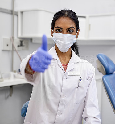 Buy stock photo Portrait of a young female dentist showing thumbs up in her office