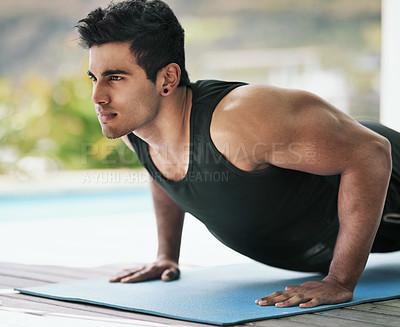 Buy stock photo Shot of a young man doing pushups during his workout at home