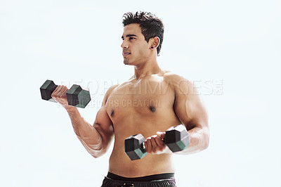 Buy stock photo Shot of a shirtless young man working out with dumbbells outside