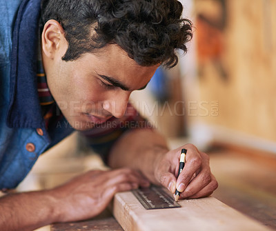 Buy stock photo Shot of a focused handyman measuring a piece of wood while working in his workshop