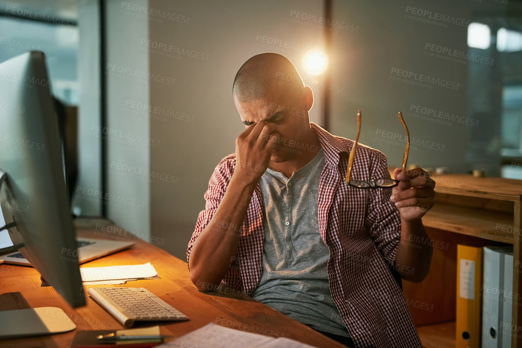 Buy stock photo Cropped shot of a young designer looking stressed out while working late in an office