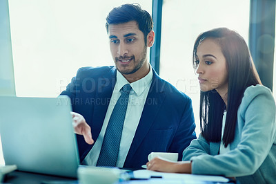 Buy stock photo Shot of a two businesspeople talking together over a laptop while working in an office