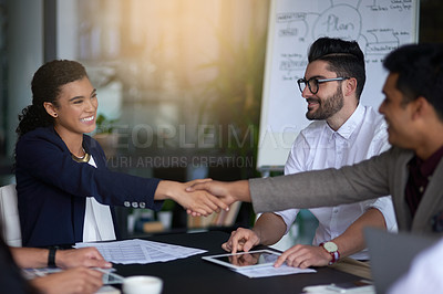 Buy stock photo Shot of two businesspeople shaking hands together in a boardroom while colleagues look on