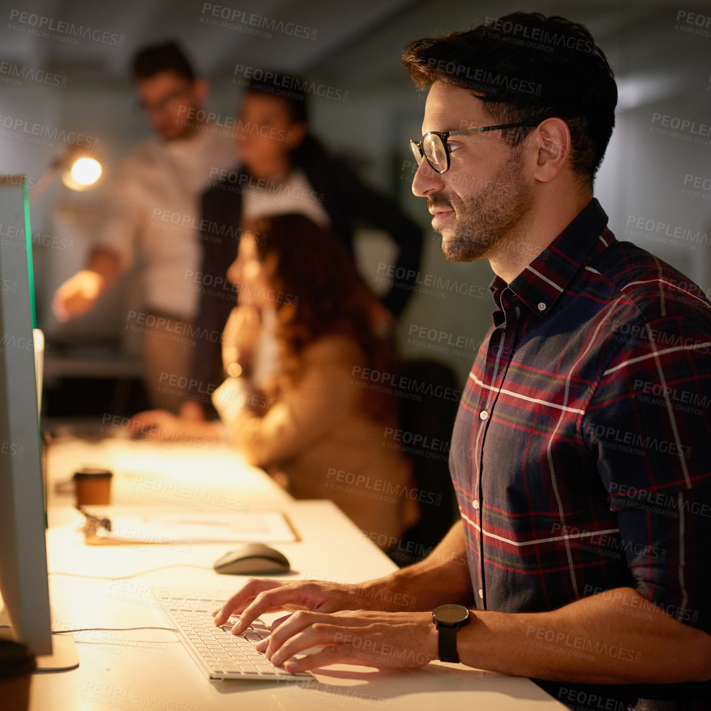 Buy stock photo Computer, typing and man at desk in office, coworkers and dark for deadline and project. Technology, pc and online work for digital designer, animator and creative at night for employee on internet