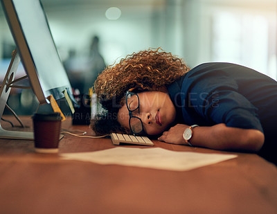 Buy stock photo Shot of an exhausted young businesswoman sleeping at her desk during a late night at work