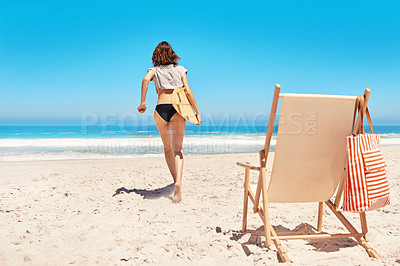 Buy stock photo Rearview shot of a sexy young woman walking towards the ocean with her surfboard