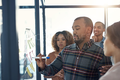 Buy stock photo Shot of a group of coworkers brainstorming on a glass wall