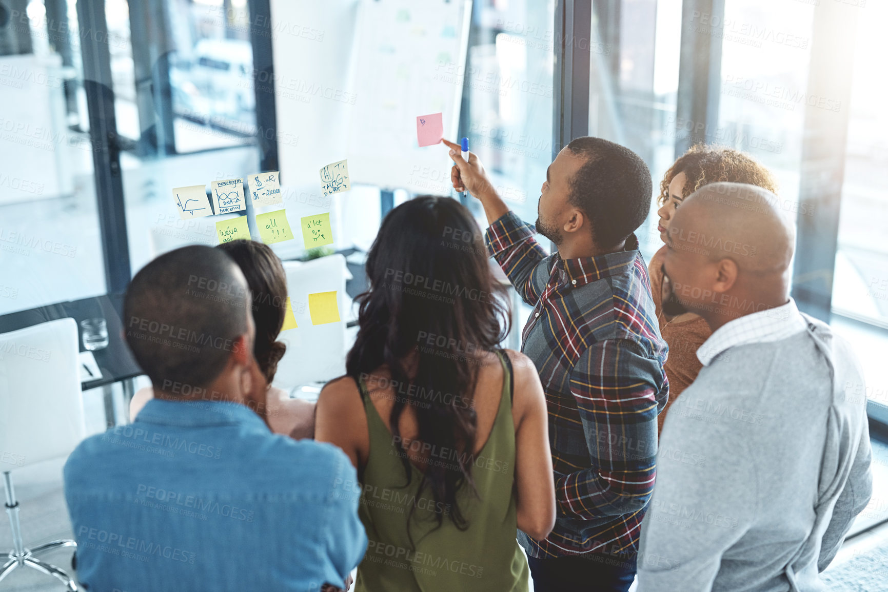 Buy stock photo High angle shot of a group of coworkers brainstorming on a glass wall