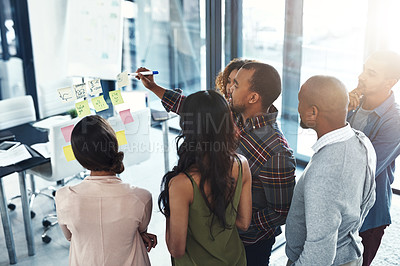Buy stock photo High angle shot of a group of coworkers brainstorming on a glass wall