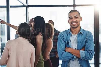 Buy stock photo Portrait of a handsome young man standing in the office with his colleagues in the background