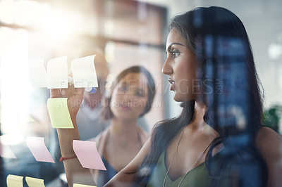 Buy stock photo Shot of a group of coworkers brainstorming on a glass wall
