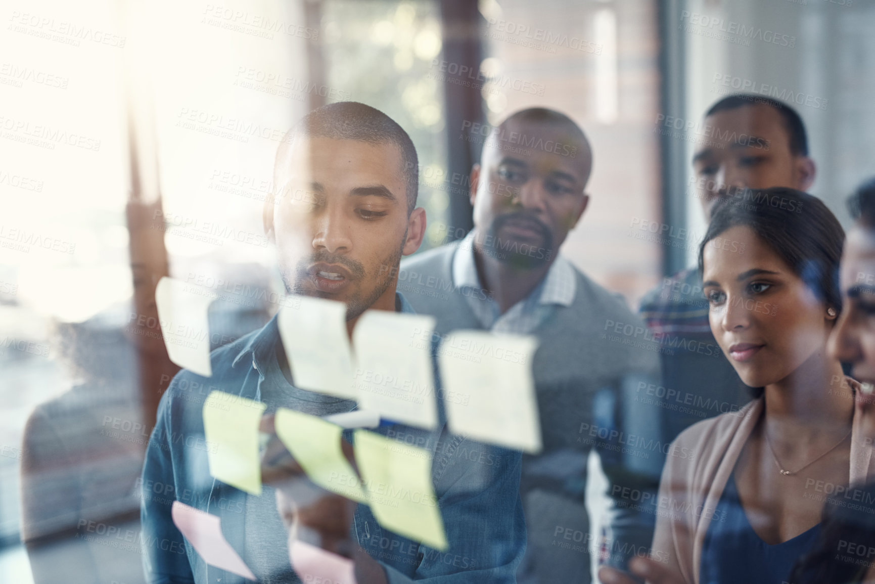 Buy stock photo High angle shot of a group of coworkers brainstorming on a glass wall