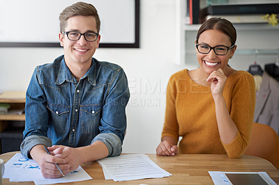 Buy stock photo Portrait of two smiling colleagues working together at a desk in an office