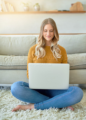 Buy stock photo Shot of an attractive young woman using her laptop while sitting on the floor at home