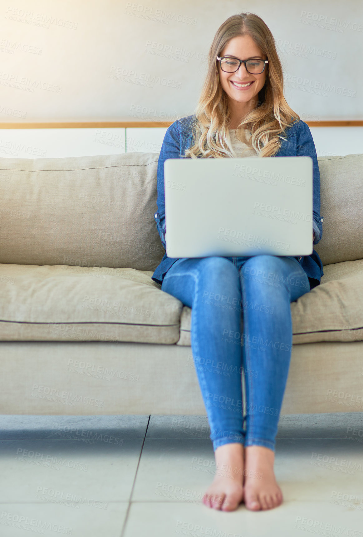 Buy stock photo Shot of an attractive young woman using her laptop while sitting on the sofa at home