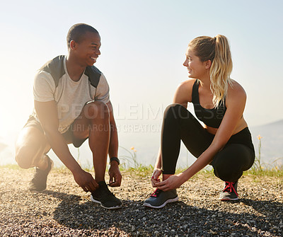Buy stock photo Shot of a fit young couple tying their shoelaces before a run outdoors