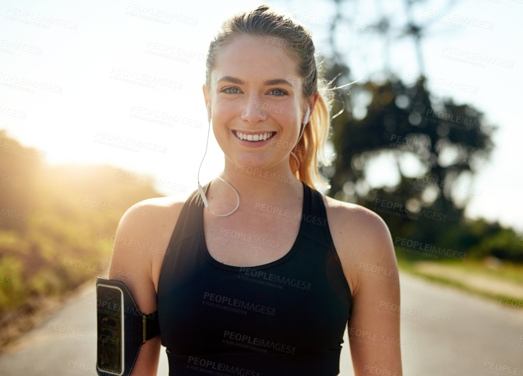 Buy stock photo Happy woman, portrait and runner with earphones on road for workout, cardio or outdoor exercise. Young, female person or athlete with smile for music, podcast or fitness on asphalt, path or street