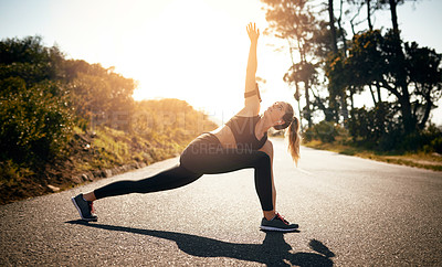 Buy stock photo Shot of a fit young woman stretching before a run outdoors