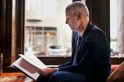 Buy stock photo Shot of a well-dressed mature man reading a menu in a cafe after work