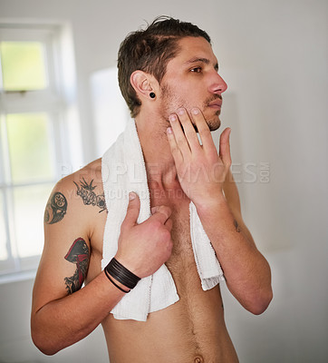 Buy stock photo Shot of a shirtless young man standing in the bathroom feeling his chin after a shave