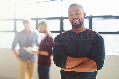 Buy stock photo Cropped portrait of a businessman standing in the office with his colleagues in the background