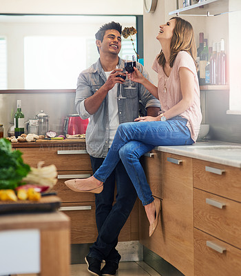 Buy stock photo Shot of an affectionate young couple drinking wine in the kitchen