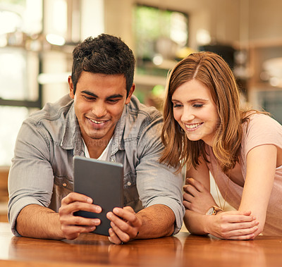 Buy stock photo Shot of a young couple using their digital tablet in the kitchen