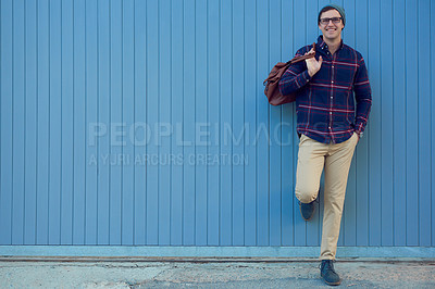 Buy stock photo Portrait of a handsome young man leaning against a blue wall