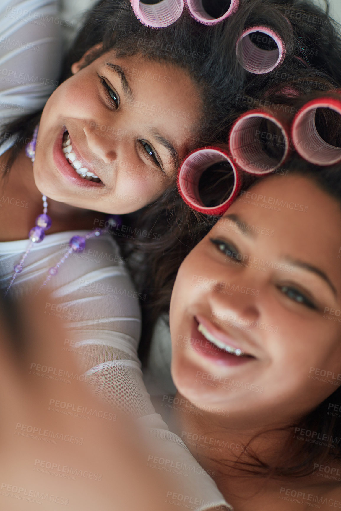 Buy stock photo Shot of a mother and her little girl taking a selfie together while wearing curlers