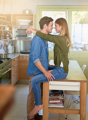 Buy stock photo Shot of an affectionate young couple hugging in their kitchen