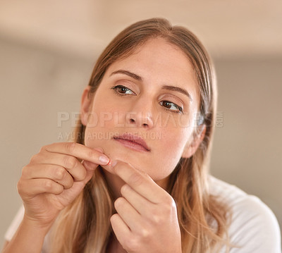 Buy stock photo Cropped shot of a young woman squeezing a pimple on her face