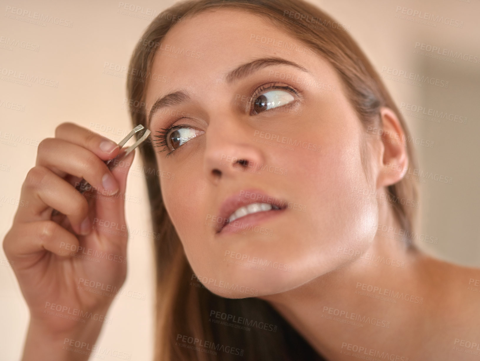 Buy stock photo Cropped shot of a young woman plucking her eyebrows with a pair of tweezers