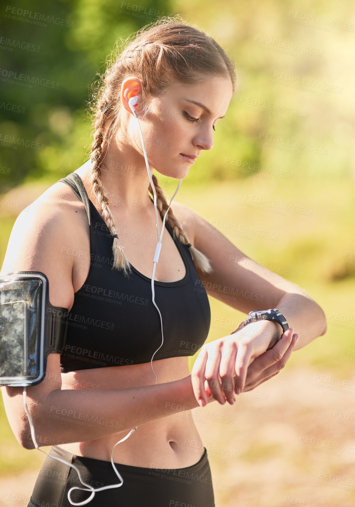Buy stock photo Shot of an attractive young woman listening to music while timing her run