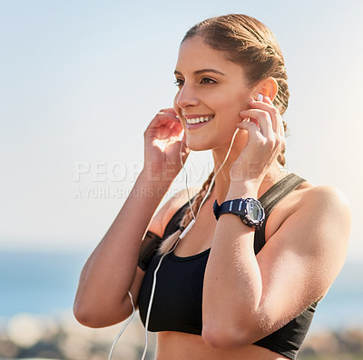 Buy stock photo Shot of an attractive young woman putting earphones in her ears in preparation for a run